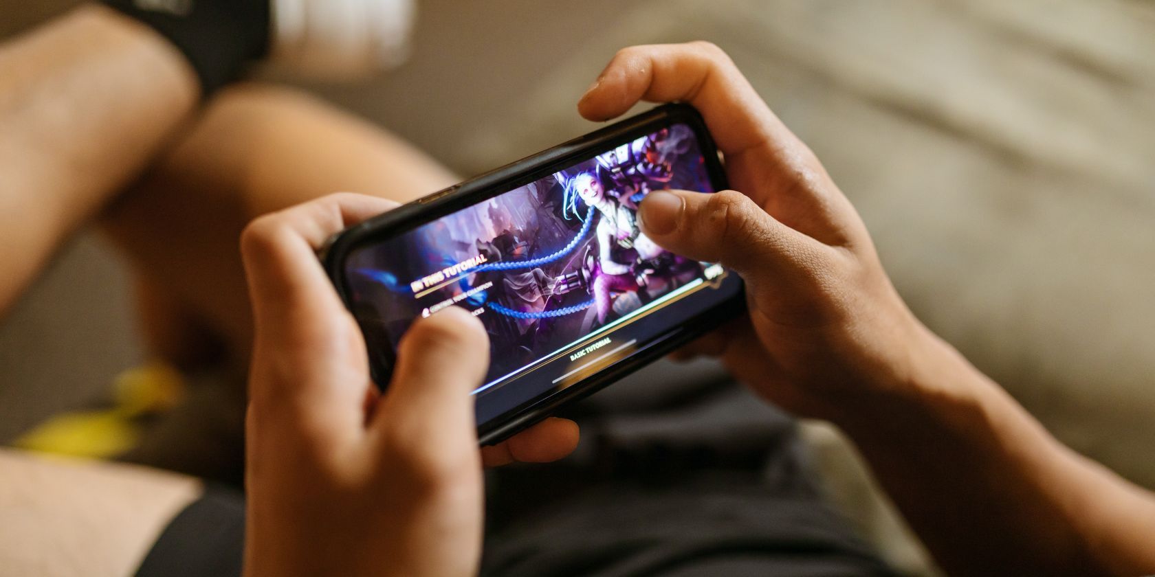 Pria bermain game seluler di sofa